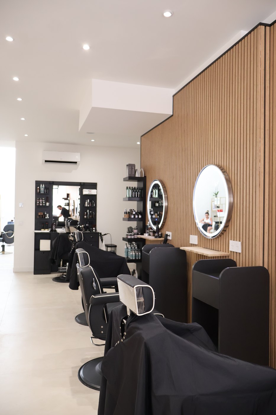 Espace AURA Men — postes barbier noir & chrome et étagères à produits
